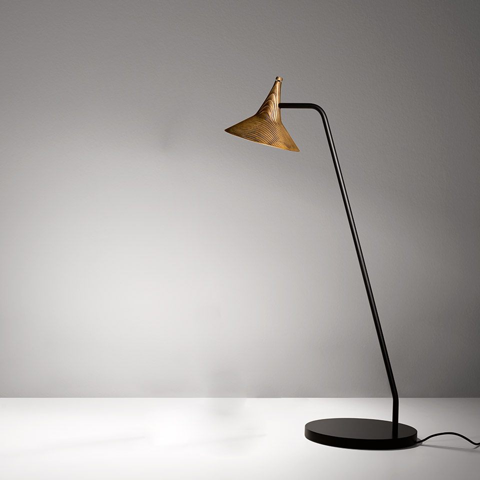 Artemide Unterlinden floor lamp: slender black stem on round base, angled arm, conical gold textured shade with ribbed pattern