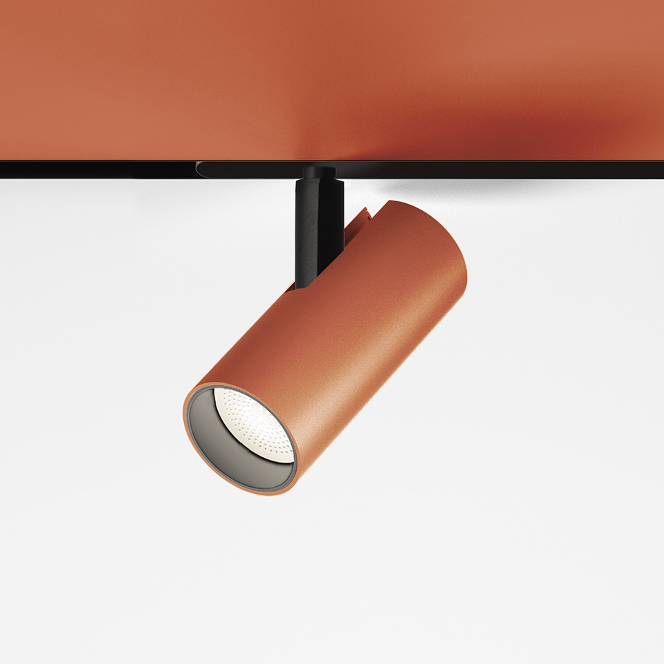 Artemide Vector Magnetic track spotlight in terracotta finish, cylindrical body on black mount, directed downward with LED light source