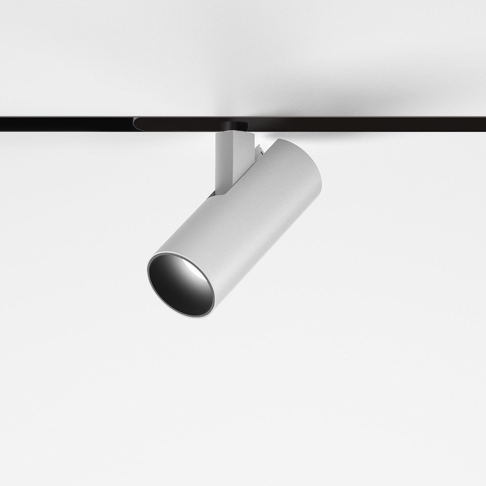 Artemide Vector Magnetic track spotlight in white, cylindrical body tilted on black magnetic rail, directional LED fixture
