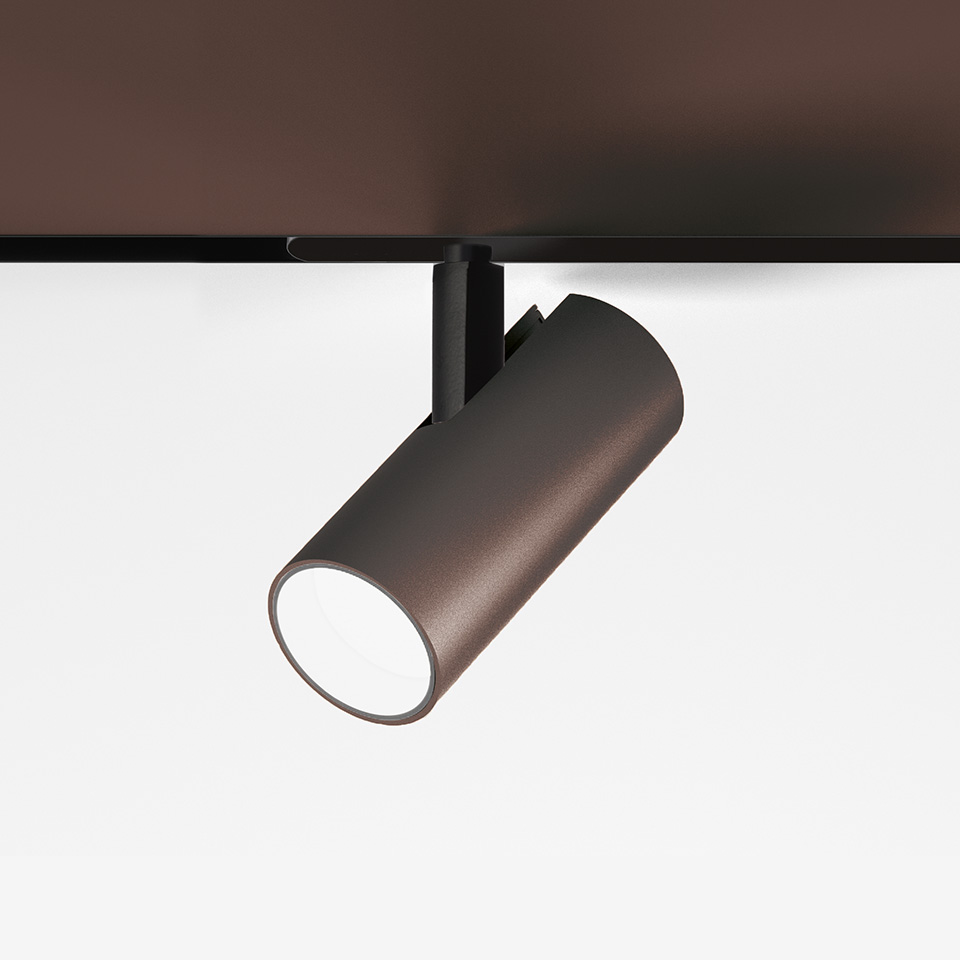 Artemide Vector Magnetic track spotlight in bronze finish, cylindrical body on black rail mount, angled downward with white LED lens