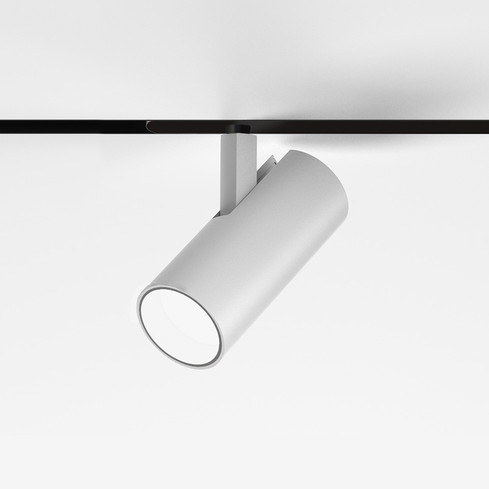 Artemide Vector Magnetic white cylindrical track spotlight, adjustable on black magnetic rail, angled downward for directional lighting