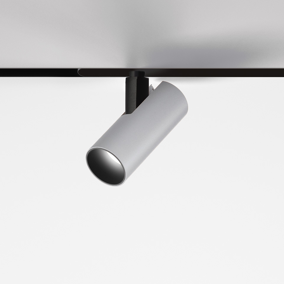 Artemide Vector Magnetic track spotlight, cylindrical white body tilted downward, mounted on black magnetic track system