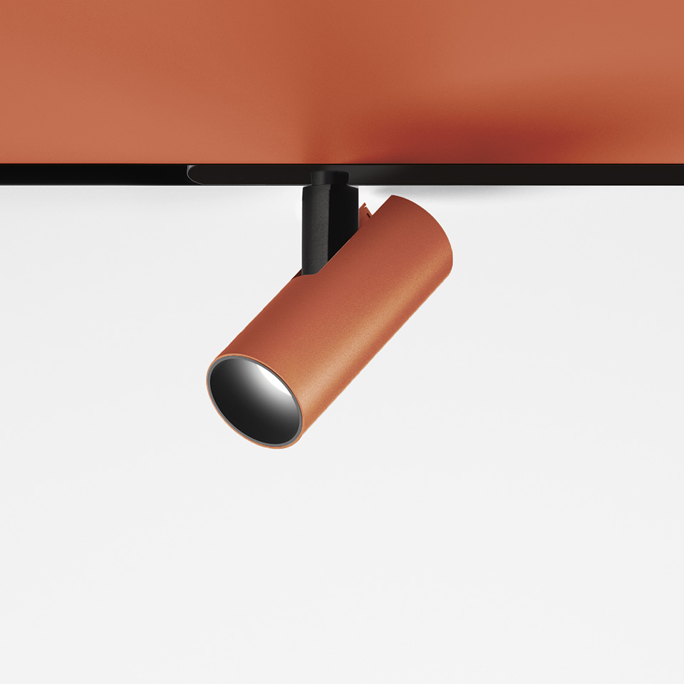 Artemide Vector Magnetic track spotlight in terracotta finish, cylindrical body on black magnetic track mount, adjustable directional head