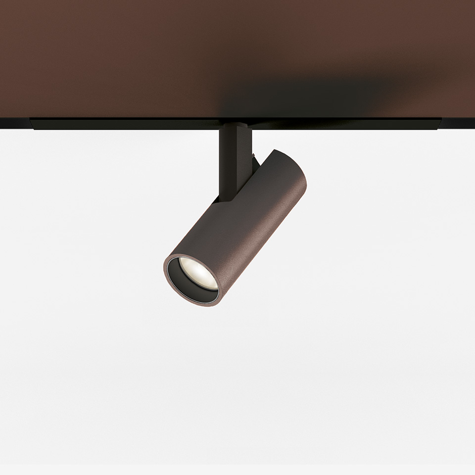 Artemide Vector Magnetic track spotlight in bronze finish, cylindrical body, mounted on black magnetic track, adjustable directional LED