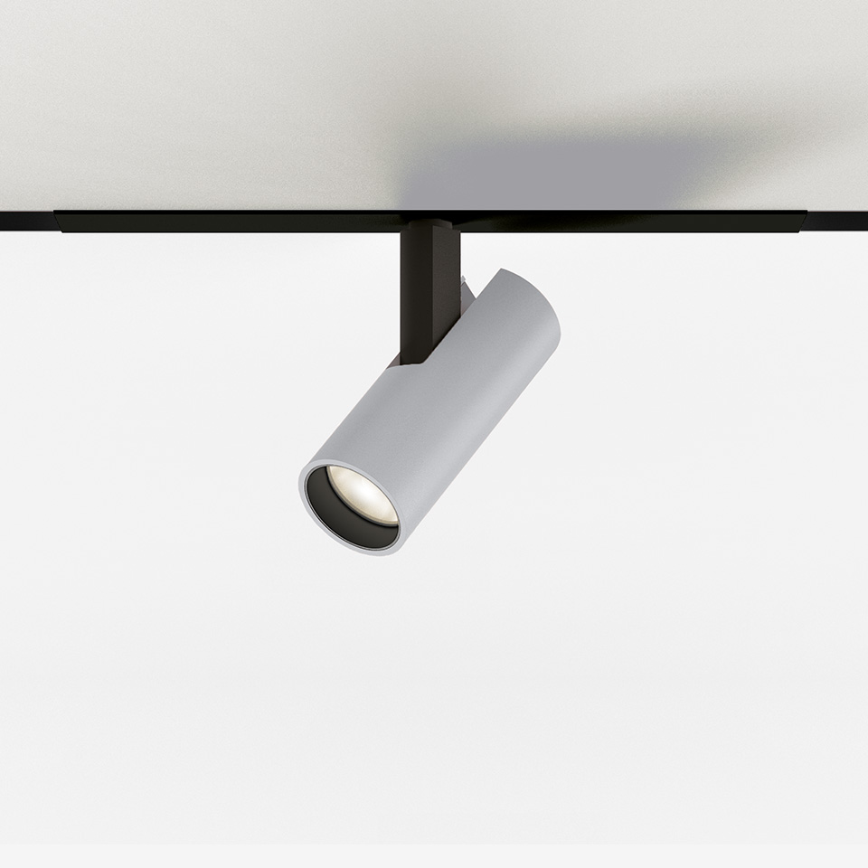 Artemide Vector Magnetic track spotlight, white cylindrical body tilted, mounted on black magnetic track, with integrated LED.
