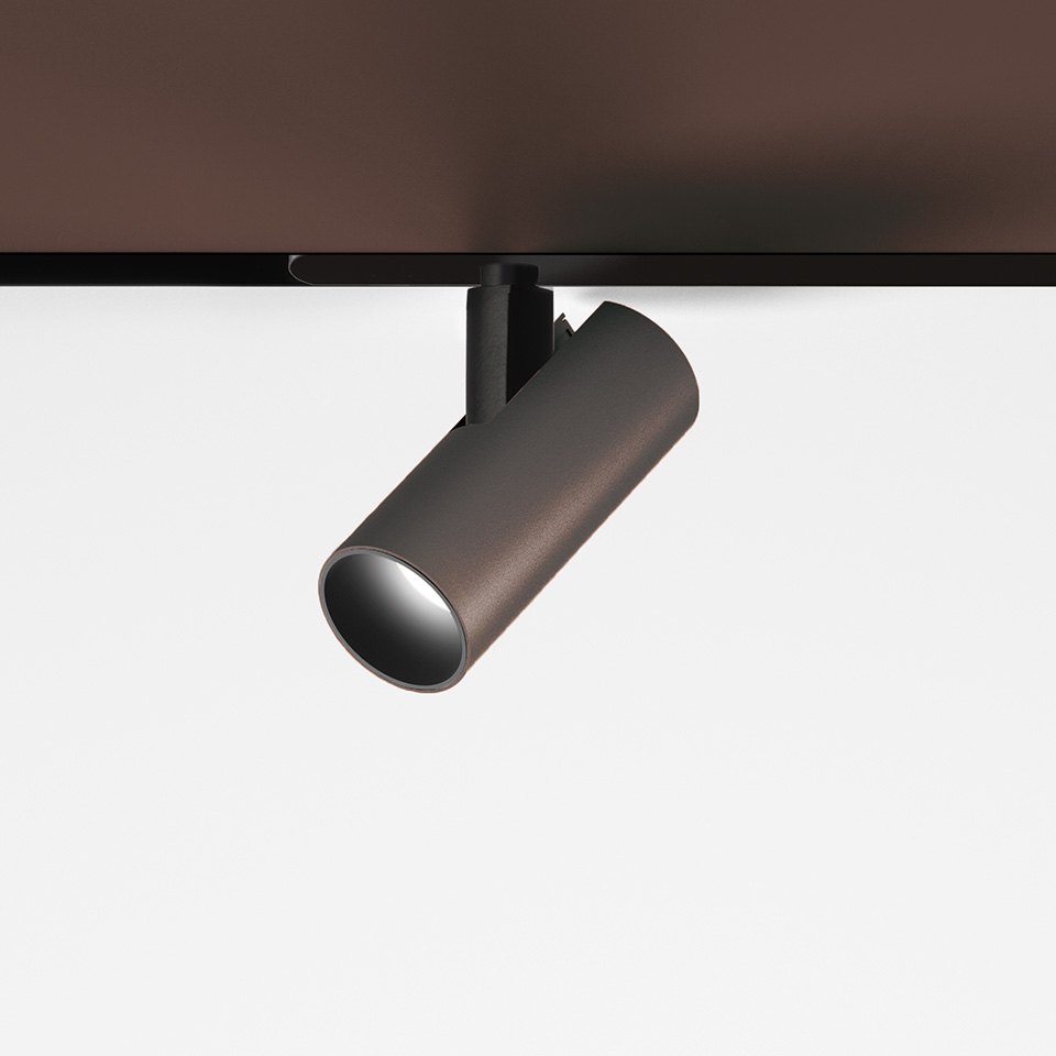 Artemide Vector Magnetic track spotlight in bronze finish, cylindrical body, adjustable head mounted on black magnetic track