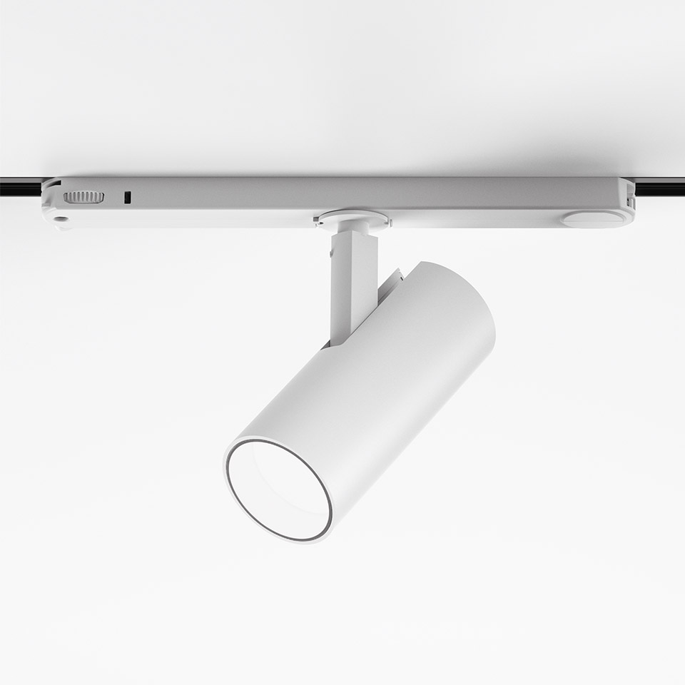 Artemide Vector Track 230V white track spotlight with cylindrical head, mounted on a ceiling rail, tilted downward.