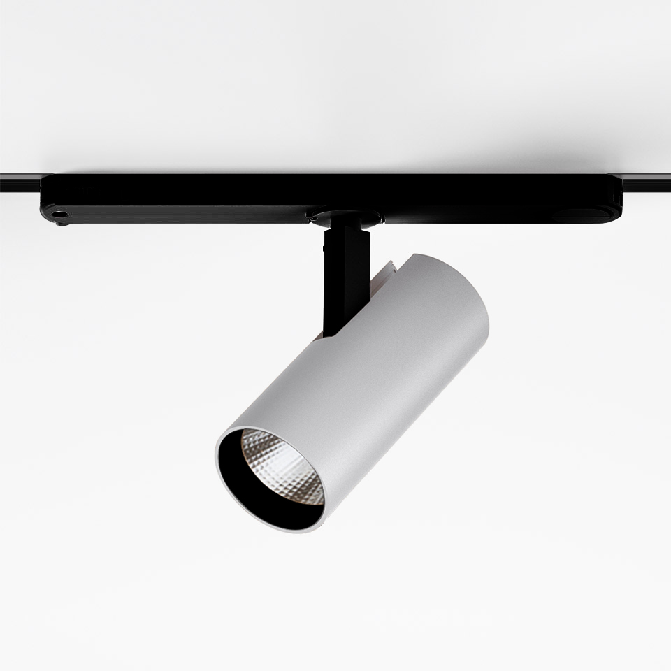 Artemide Vector Track 230V: white cylindrical LED spotlight mounted on black track rail, tilted downward for directional lighting