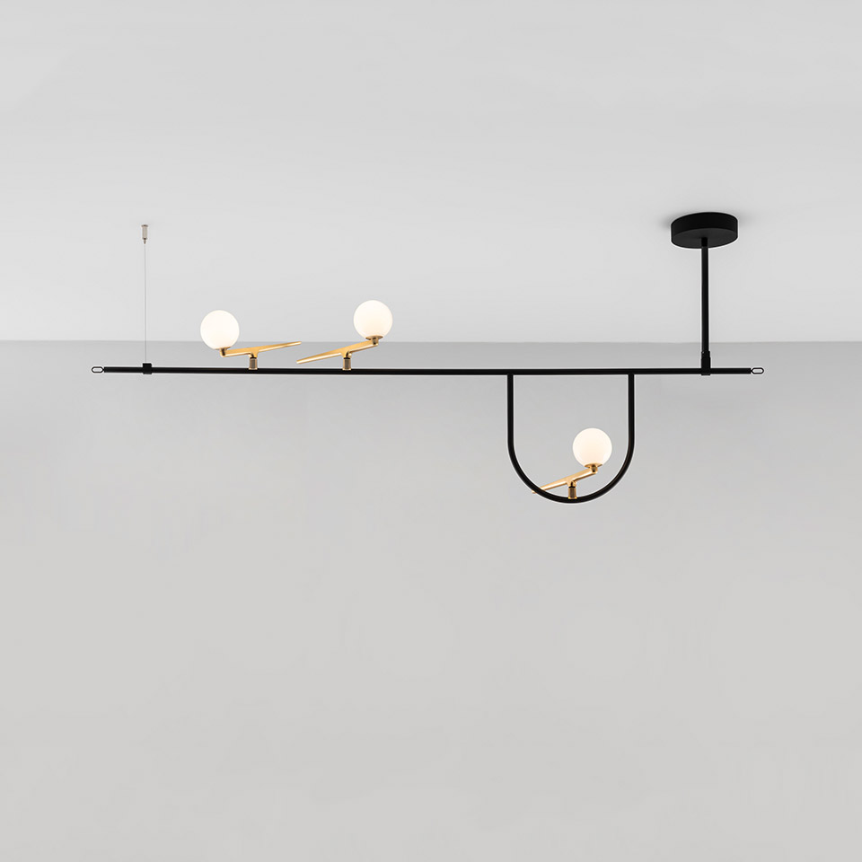 Artemide Yanzi ceiling lamp: black horizontal bar with brass accents, three opal glass globe shades at varying heights and angles