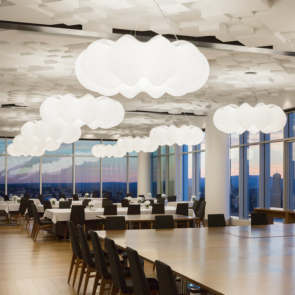 Artemide cloud-shaped white pendant lights suspended over a modern restaurant dining room with panoramic city views at dusk