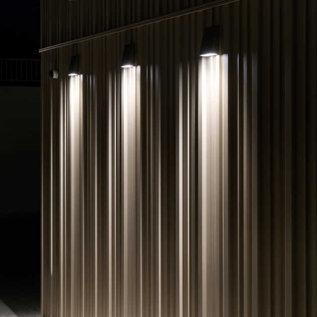 Detail of the exterior lighting on the façade of the new Fornaroli Polymers headquarters, with Cuneo wall-mounted luminaires projecting vertical beams of light.