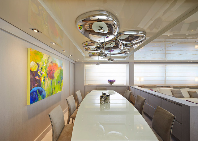 Yacht dining room with Artemide Mercury chandelier in polished chrome suspended over a white oval table surrounded by beige chairs.