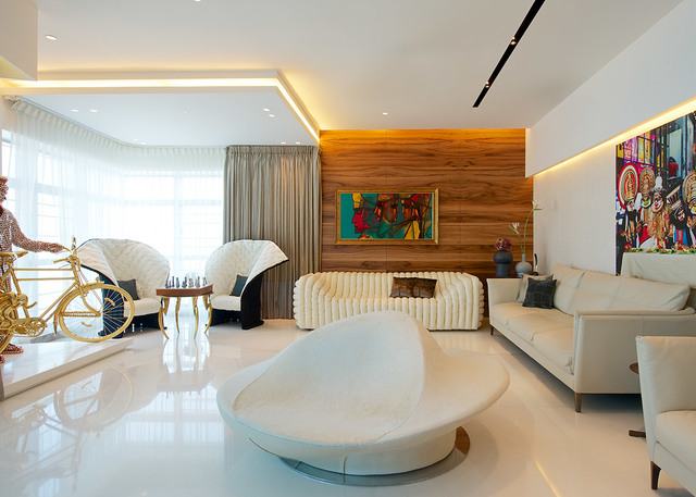 Modern living room with cove lighting, recessed ceiling lights, white sculptural furniture, wood accent wall, and colorful artwork.