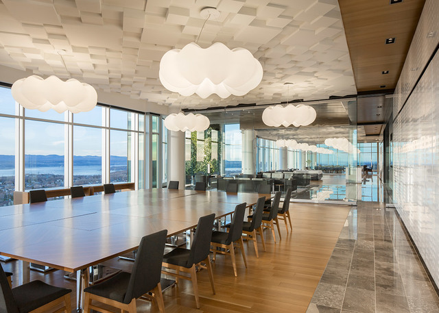 Modern conference room with Artemide Nebula pendant lamps resembling clouds, suspended over a long wooden table with city and water views.
