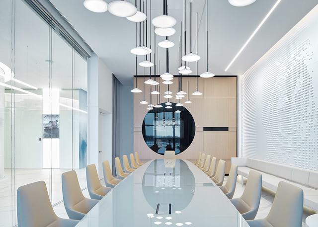 Modern conference room with a cluster of white disc pendant lights hanging at varying heights over a long white table with beige chairs