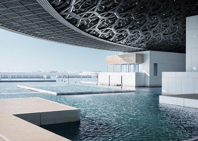 Louvre Abu Dhabi museum exterior with iconic geometric dome over water channels and white pavilions under clear blue sky