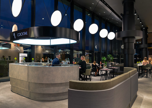 Modern cocktail bar with circular pendant lamp and spherical white globe pendants illuminating seating areas and bar counter.