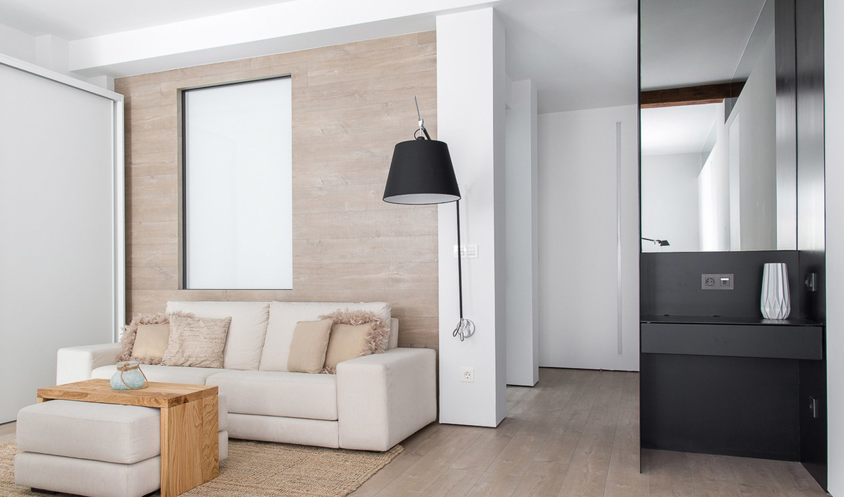 Modern living room with a black conical floor lamp beside a white sofa, neutral tones, wood accents, and a glimpse of a bathroom.