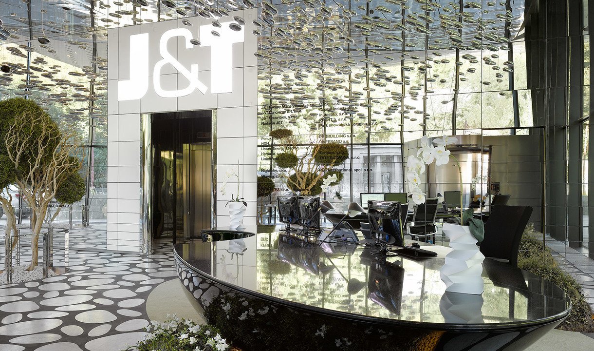 J&T building lobby with reflective ceiling, elegant black reception desk, white sculptural lamps, and mirrored decorative panels