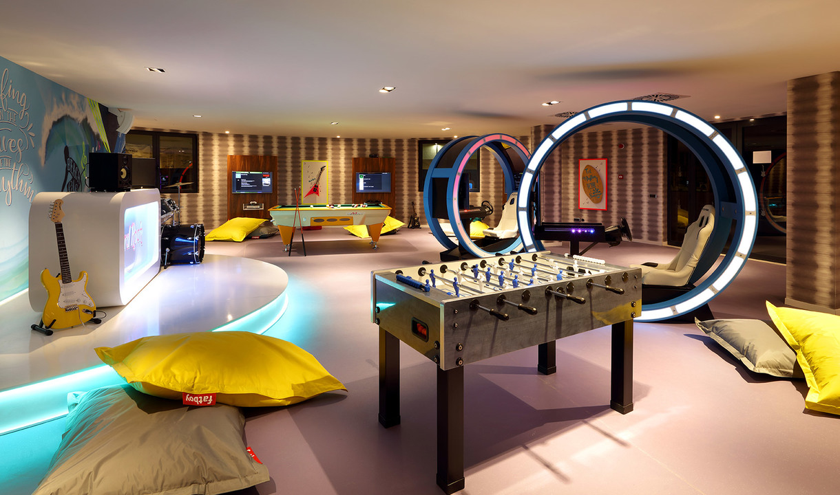 Vibrant game room with foosball table, circular illuminated portals, bean bags, pool table, and ambient LED lighting accents.