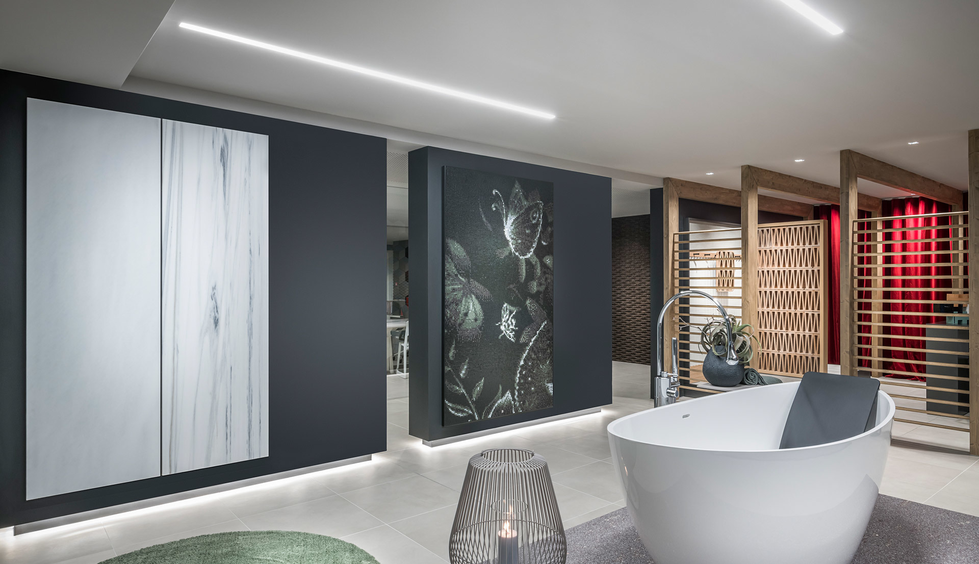 Modern showroom with freestanding white bathtub, recessed linear LED ceiling light, decorative wall panels, and warm accent lighting.