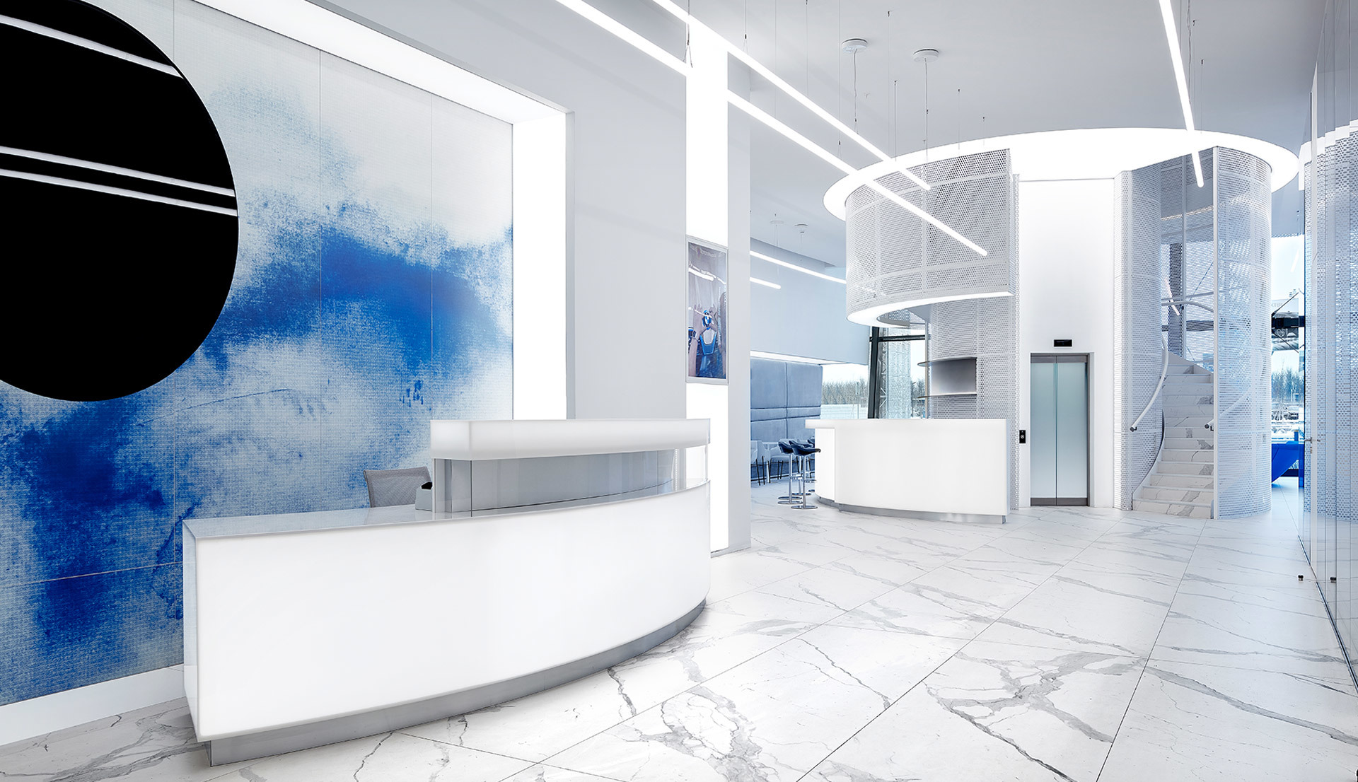Modern white reception lobby with marble floors, blue wall art, and Artemide circular pendant and recessed linear ceiling lights