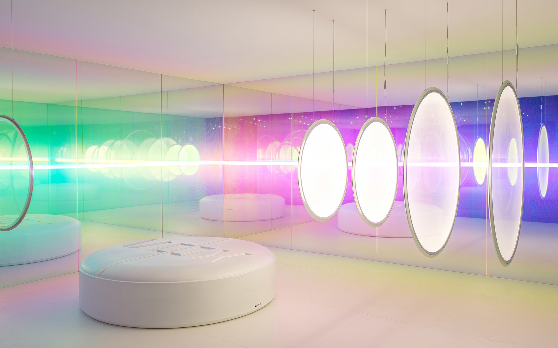 Futuristic showroom with oval pendant lights emitting colorful iridescent glows in pink, green, and purple on mirrored white walls
