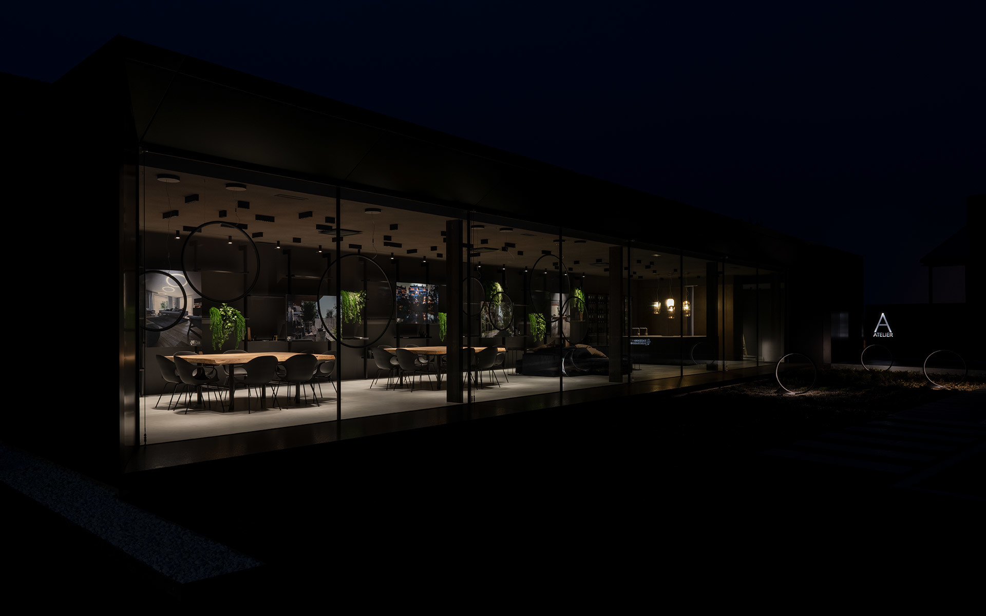 Glass-walled restaurant or showroom illuminated at night, featuring pendant lights, greenery, and a long dining table visible from outside.