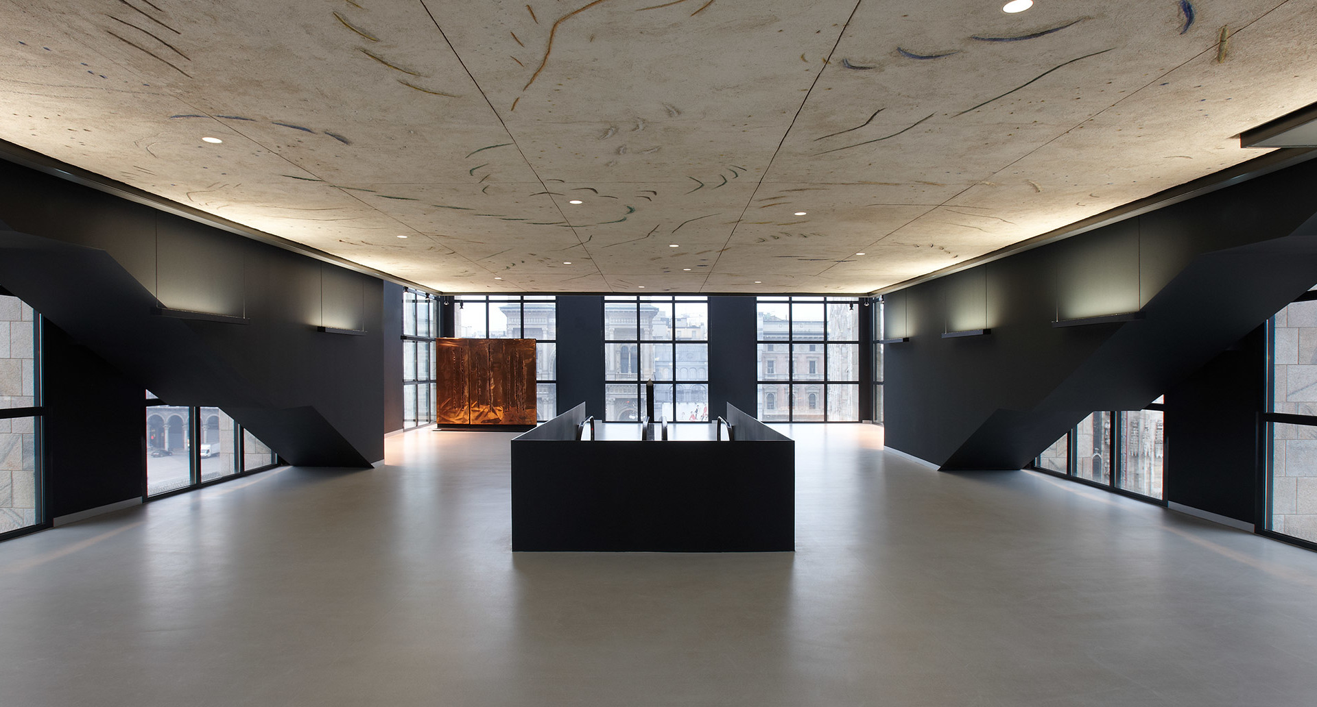 Spacious modern interior with recessed ceiling lights illuminating a textured wood ceiling, black geometric partitions, and a central dark display unit.
