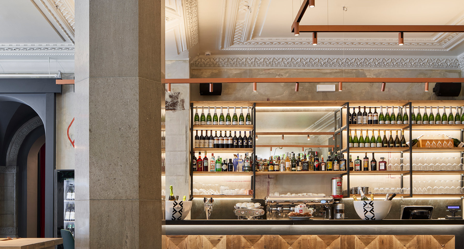Elegant bar interior with backlit shelves displaying wine bottles, warm LED strip lighting highlighting a well-stocked bar counter