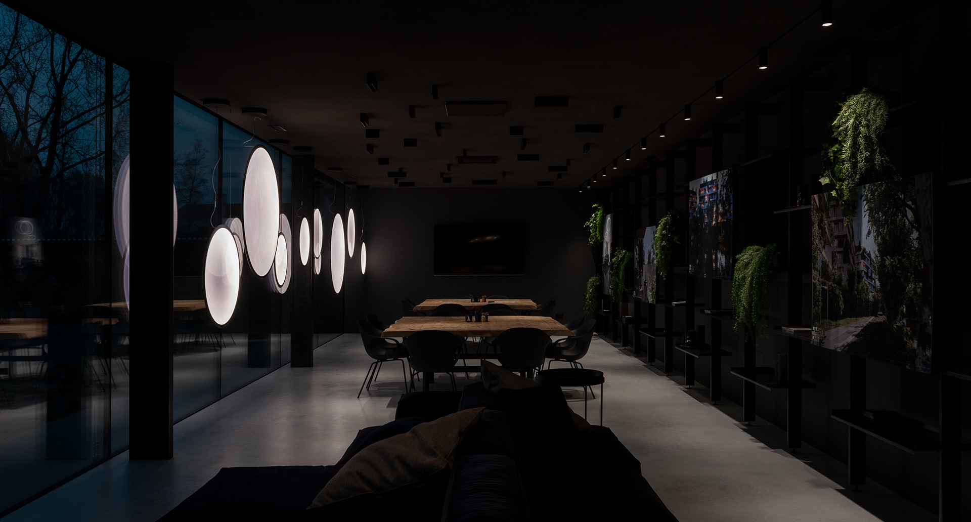 Dark modern dining room with glowing circular pendant lights, wooden table, black chairs, and living green wall accents.
