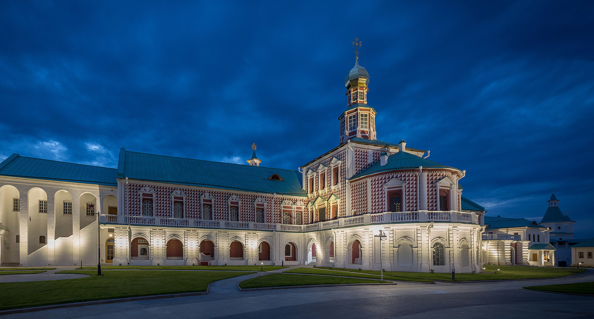 Historic baroque building illuminated at dusk by warm architectural lighting, highlighting ornate facade details against a dramatic blue sky