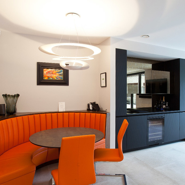 Artemide Pirce pendant lamp with concentric rings illuminates a modern dining area with orange curved booth seating and chairs