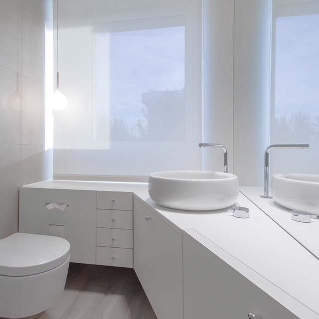 Minimalist white bathroom with vessel sink, wall-mounted faucet, and a small spherical pendant lamp providing soft ambient light.