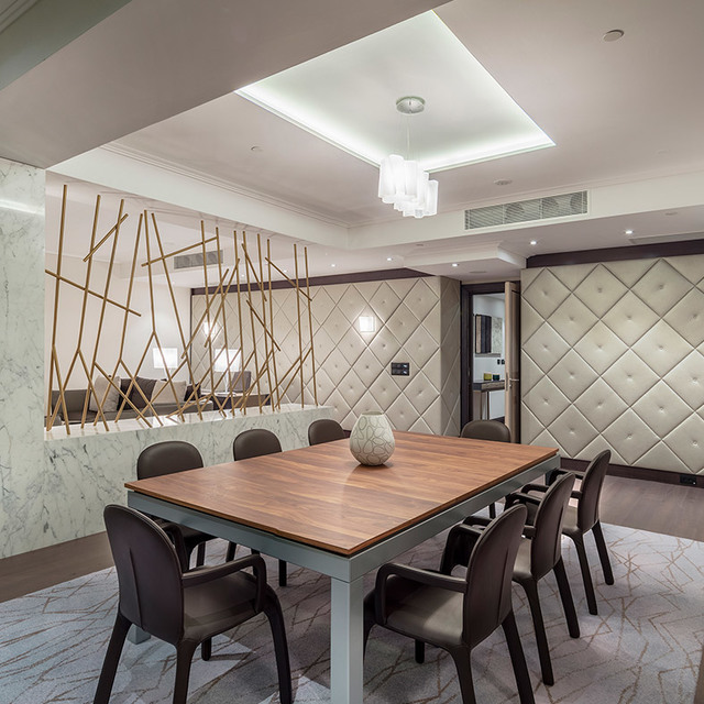 Elegant dining room with walnut table, dark chairs, and a cascading glass pendant light over a coffered ceiling.