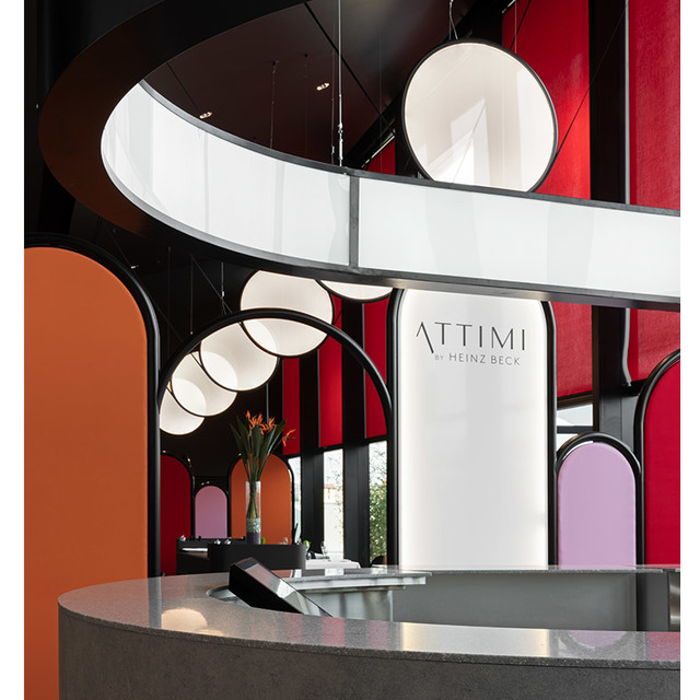 Attimi by Heinz Beck restaurant interior with circular pendant lamps featuring white opal discs on black arched frames, bold red and orange decor.