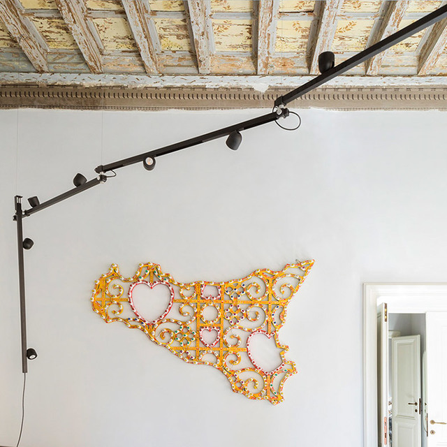 Artemide black wall-mounted track light with multiple adjustable spotlights, installed in a room with ornate ceiling and decorative wall art.