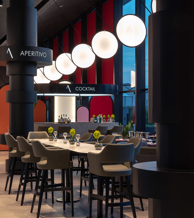 Restaurant bar area with a row of six Artemide spherical white globe pendant lights above high tables and gray bar stools.