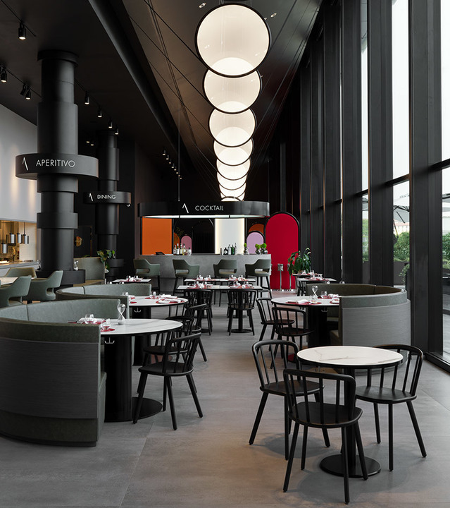 Modern restaurant interior with cascading spherical white pendant lights hanging from high ceiling above dark furniture and round tables.