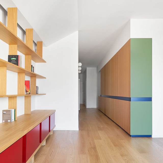Modern interior with wood shelving, colorful red and green cabinetry, and three white spherical pendant lights illuminating a hallway.