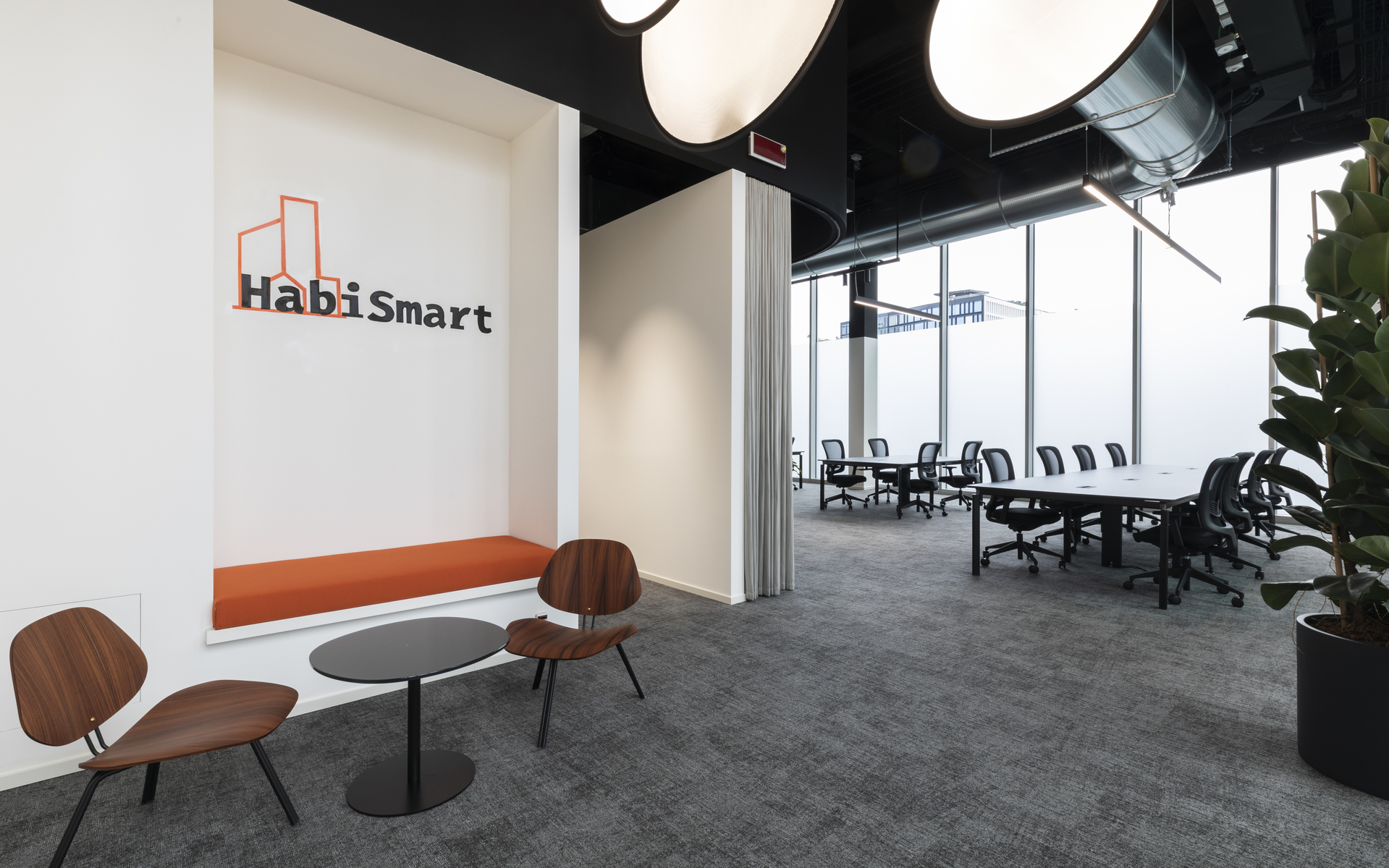 HabiSmart office with large round pendant lights, a conference table, seating area with wooden chairs, and floor-to-ceiling windows