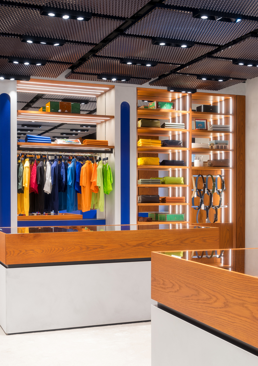 Modern retail store interior with Artemide recessed ceiling spotlights illuminating colorful clothing racks and warm-lit wooden shelving units.