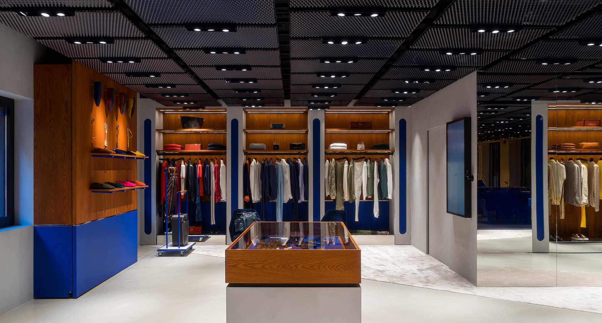 Modern retail store interior with Artemide recessed ceiling spotlights illuminating clothing displays, wooden shelving, and a central showcase.