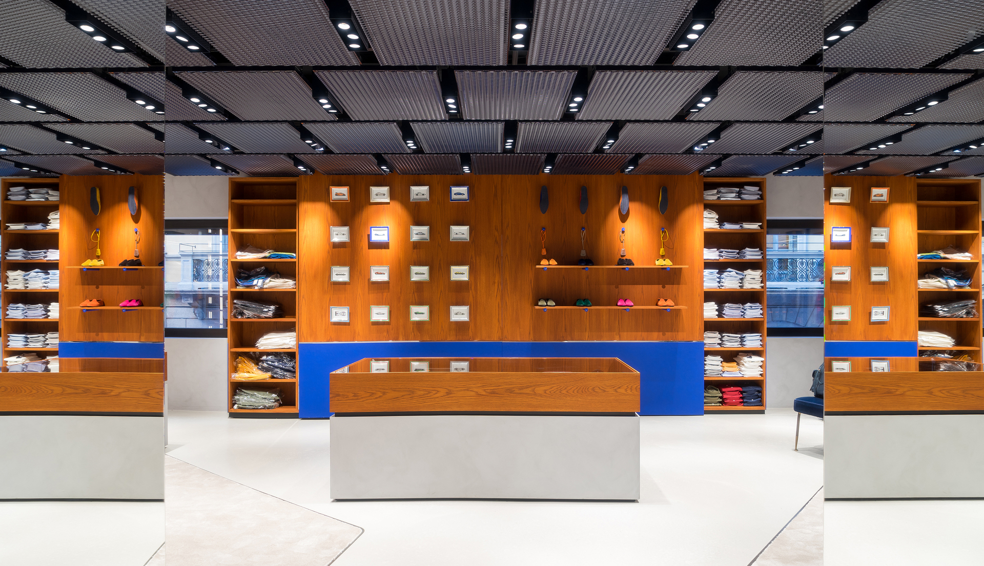 Modern retail store interior with warm wood shelving, blue accents, and Artemide recessed spotlights illuminating displayed products on ceiling grid.