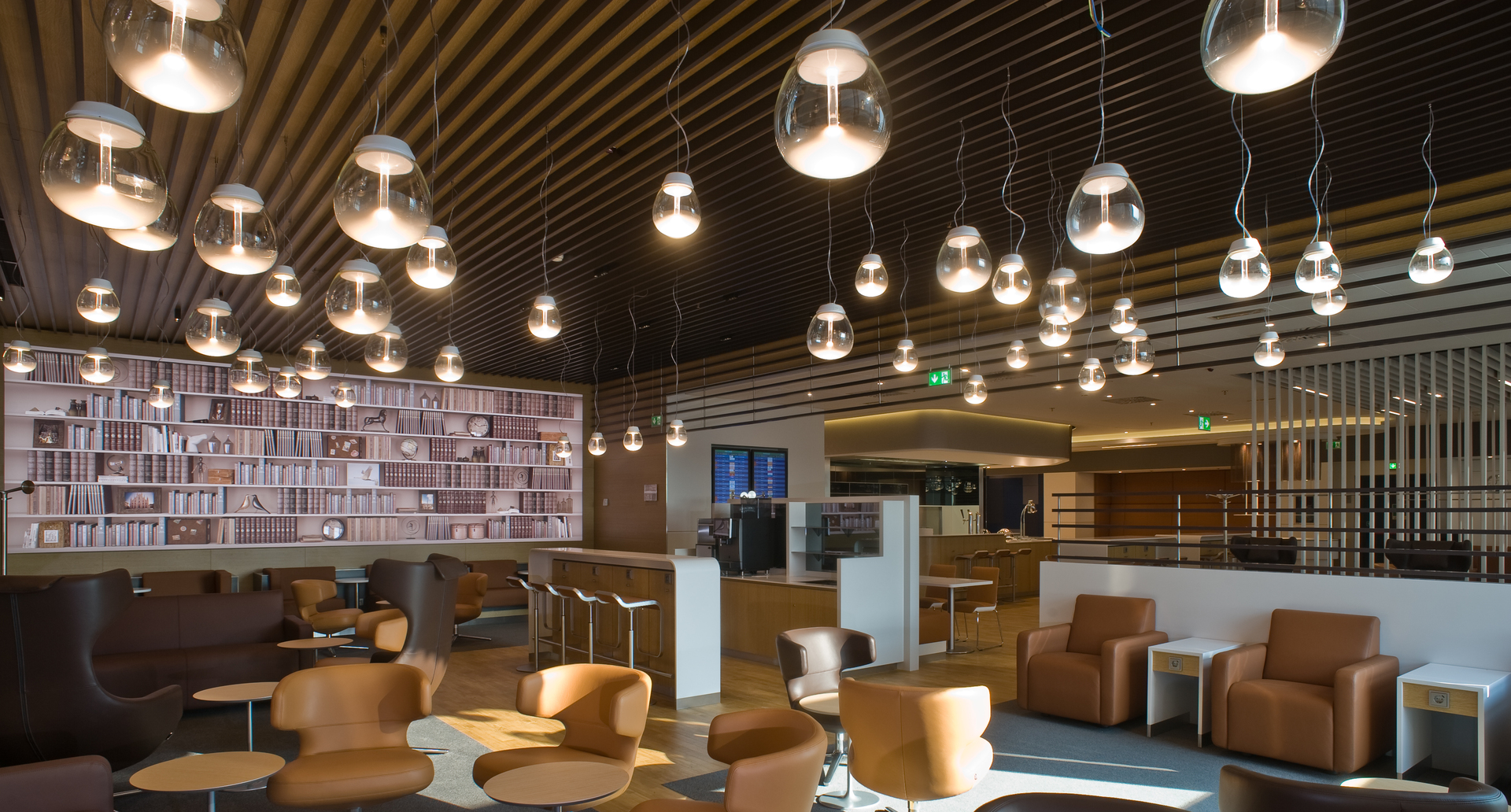 Lounge interior with multiple Artemide Muse pendant lamps in transparent glass hanging at varying heights over seating area.