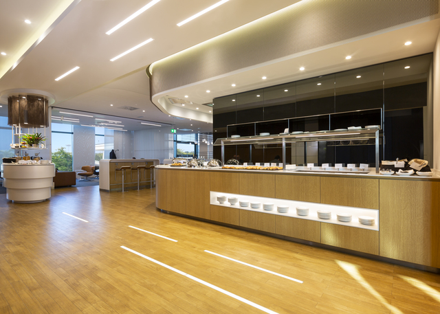 Modern restaurant buffet area with recessed ceiling lights and linear LED strips illuminating warm wood counters and flooring.
