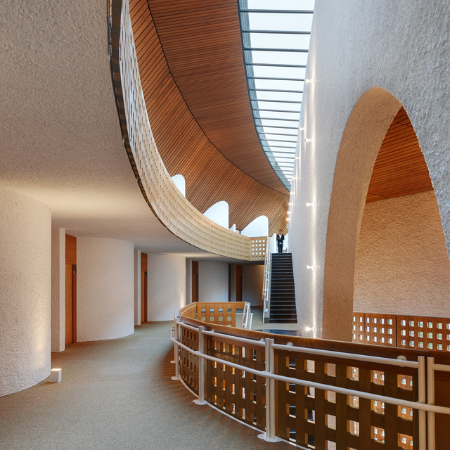 Curved interior corridor with arched openings, warm wood ceiling, textured white walls, and vertical LED strip lighting along a staircase.