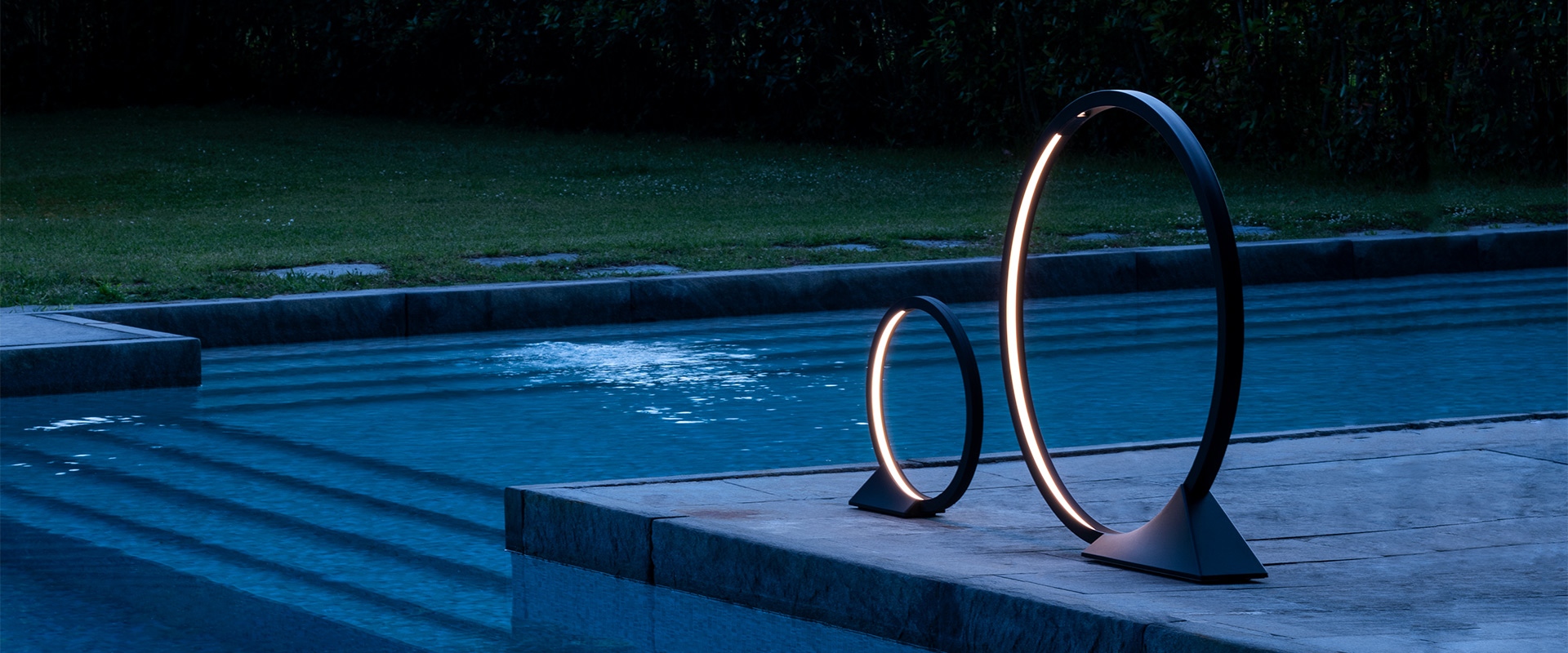 Three Artemide 'O' pendant lights in matte black, circular rings of varying sizes suspended from thin cables