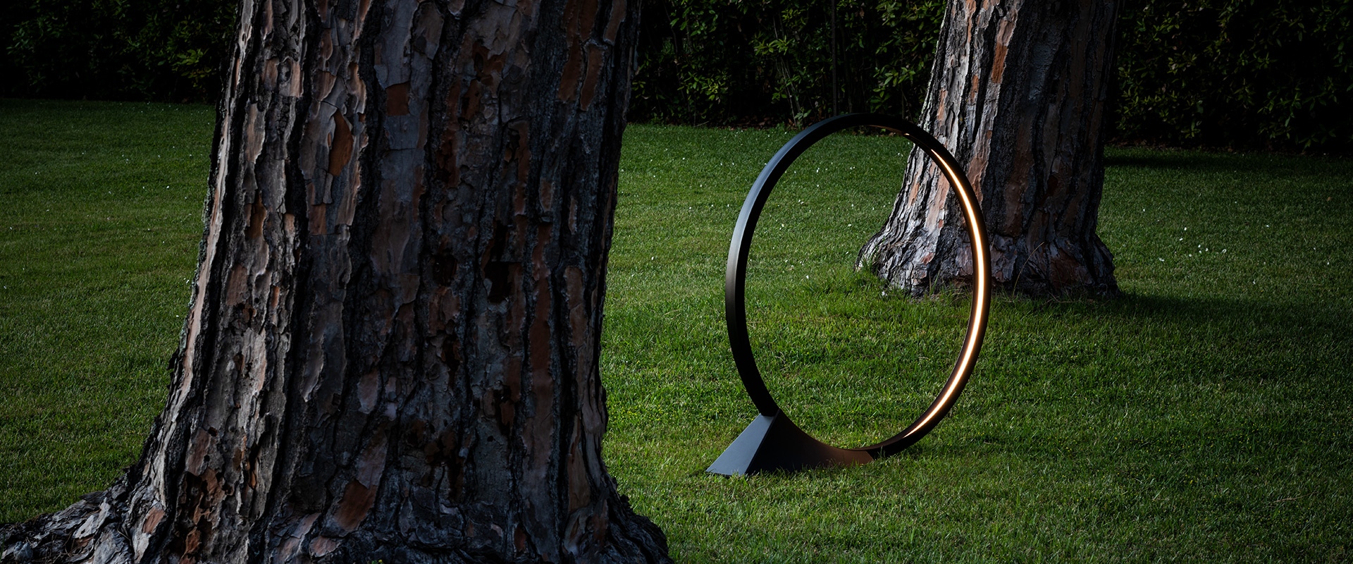 Three Artemide 'O' LED table lamps in black with gold inner ring, in small, medium, and large sizes on triangular bases