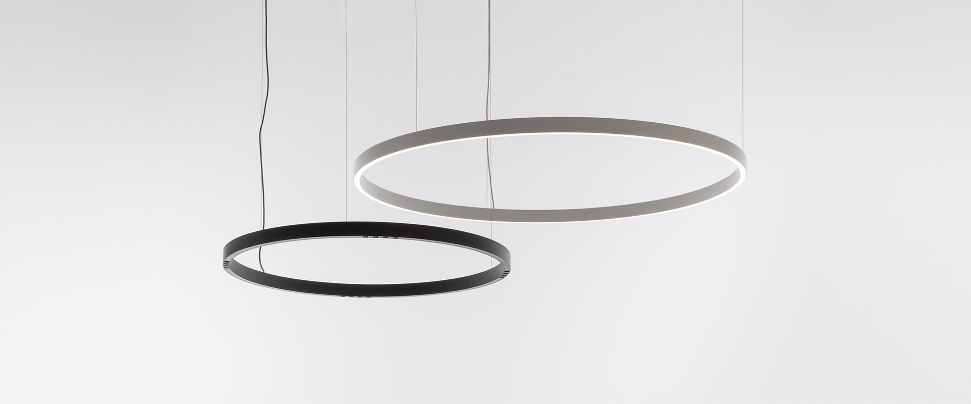 Artemide A.24 Circolare Stand-alone black circular LED pendant lamp suspended over a wooden shelf with decorative objects